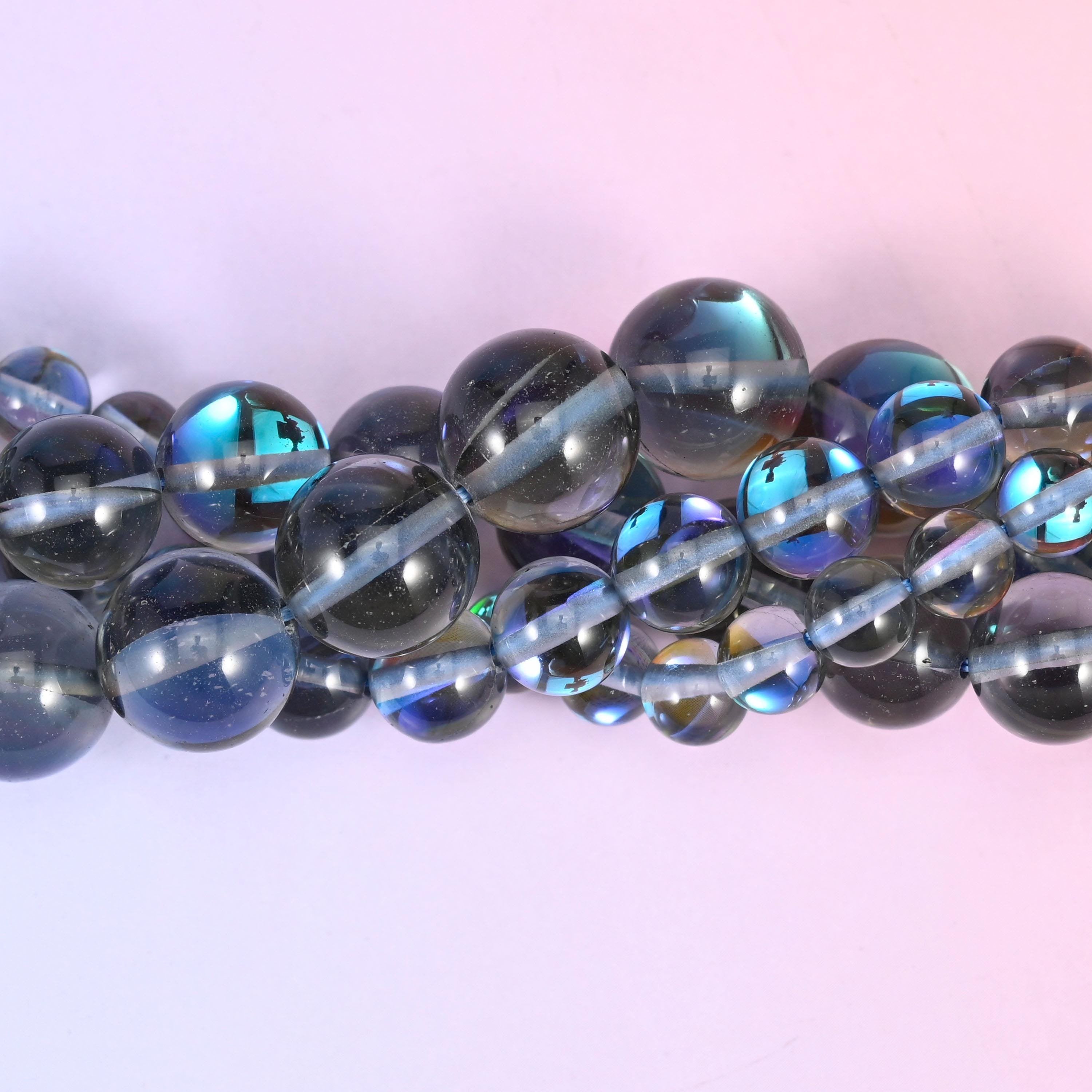 Smoky grey glass rounds with a high glossy polish lit by a strong peacock flash of blue, green and violet