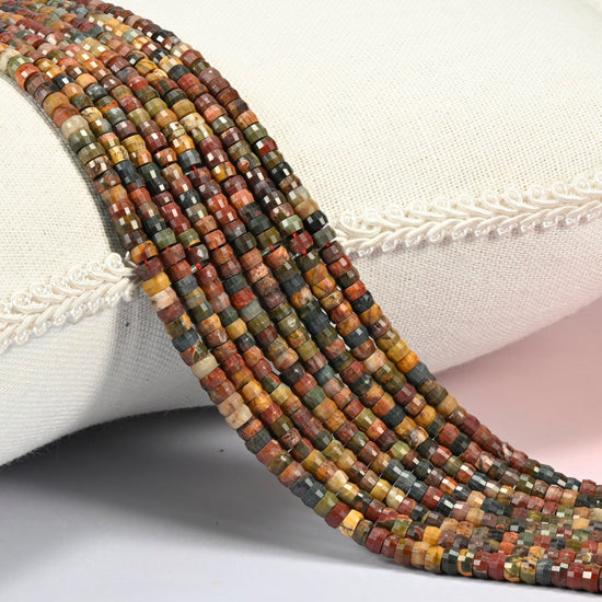 Red howlite faceted heishi disc beads 2x4mm, several strands draped over a white cushion
