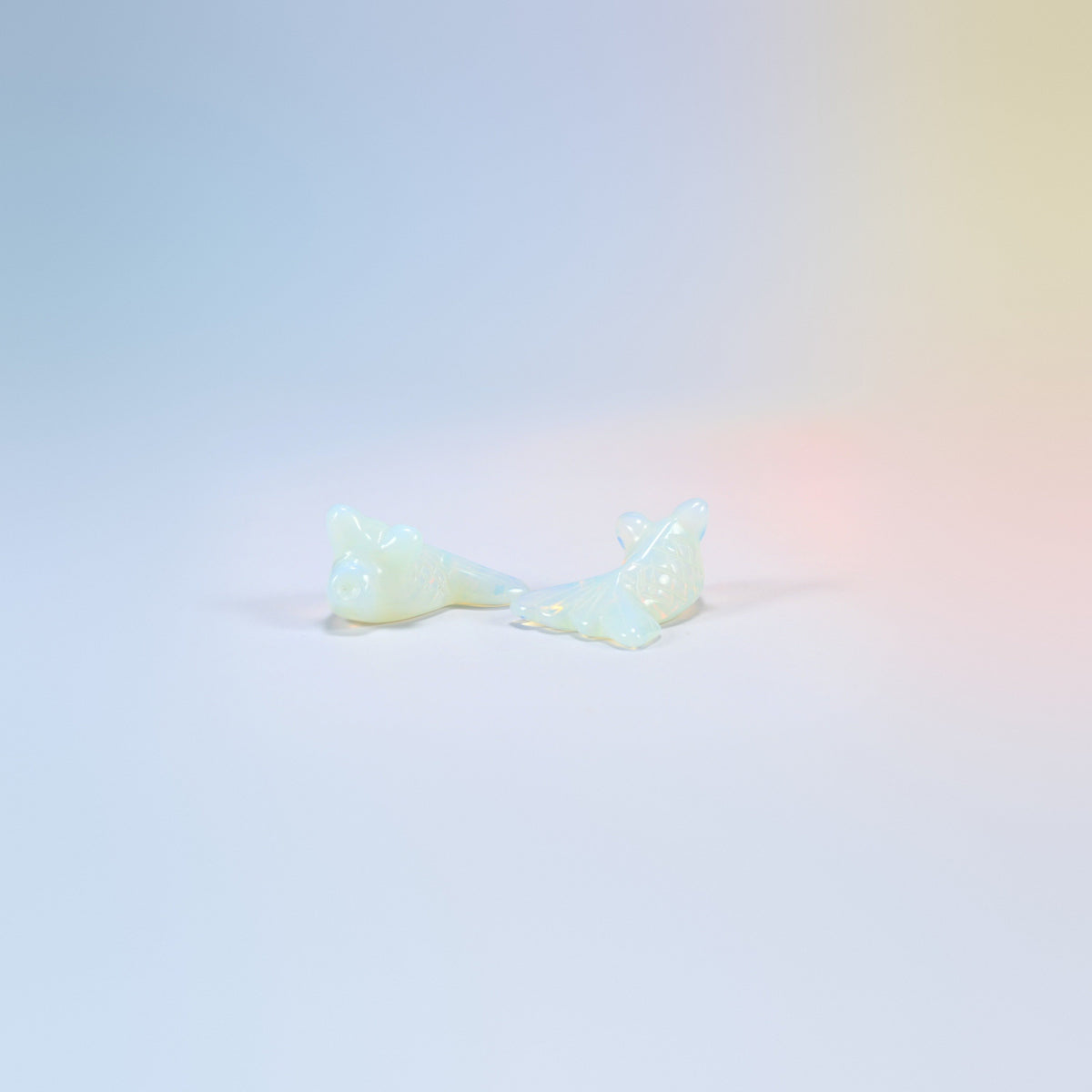 Two 1.5 inch opalite goldfish carvings, milky man-made glass with a soft glow