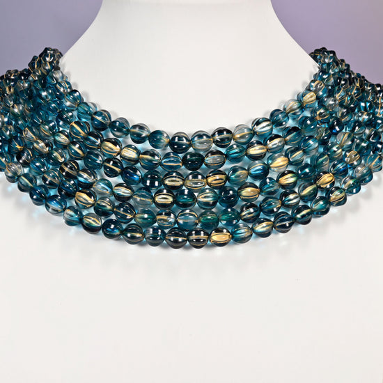 Dark blue gold pumpkin glass beads shown as layered strands on a white neck display form.