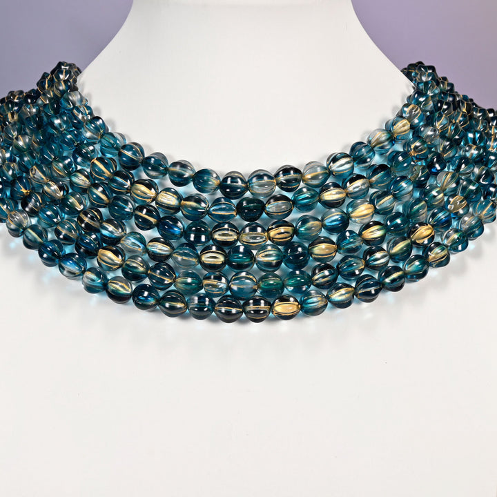 Dark blue gold pumpkin glass beads shown as layered strands on a white neck display form.