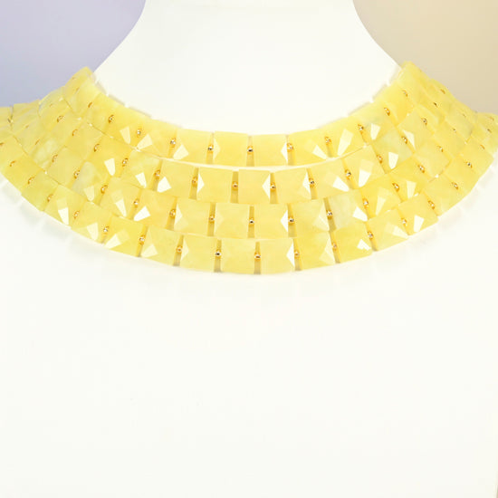 Lemon Jade faceted flat square strands arranged as a layered collar on a white display bust, light yellow beads across the neck