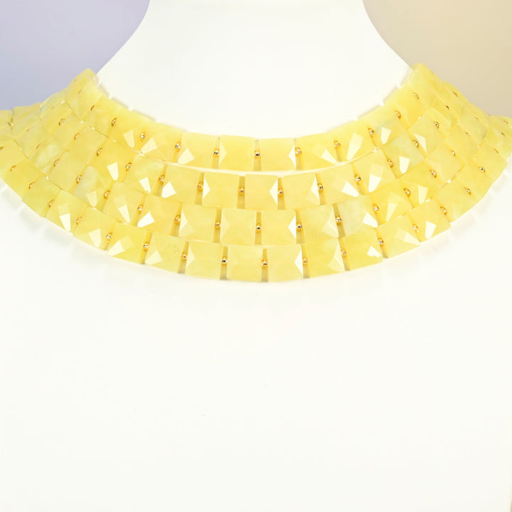 Lemon Jade faceted flat square strands arranged as a layered collar on a white display bust, light yellow beads across the neck