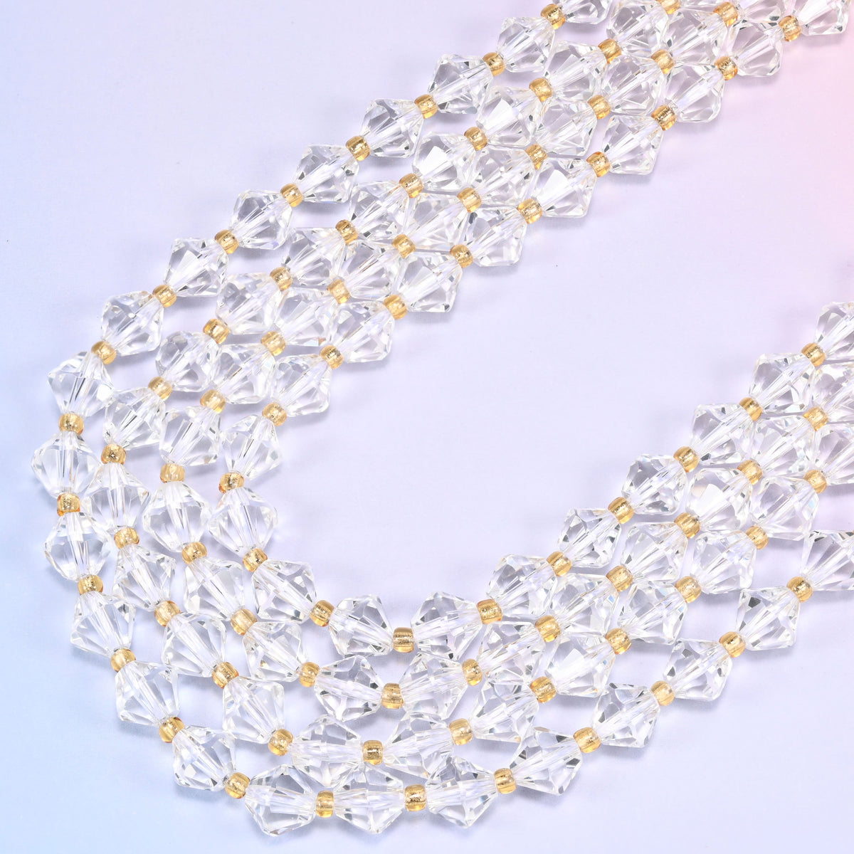 8mm Clear Quartz faceted bicone beads arranged in a loose curved strand on a light lavender background.