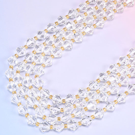 8mm Clear Quartz faceted bicone beads arranged in a loose curved strand on a light lavender background.