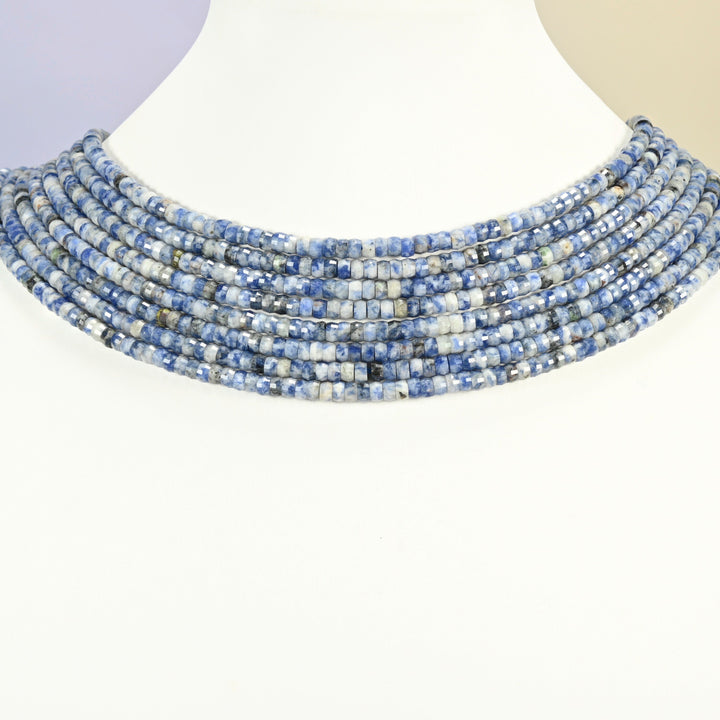Blue spot jasper faceted heishi disc strands arranged as a layered collar on a white display bust, blue and white beads across the neck