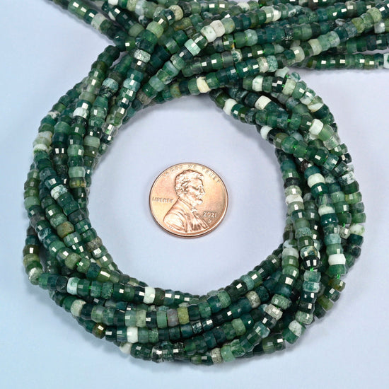 Moss agate faceted heishi disc beads 2x4mm coiled in a loop around a US penny for scale, close-up of the faceted disc shape