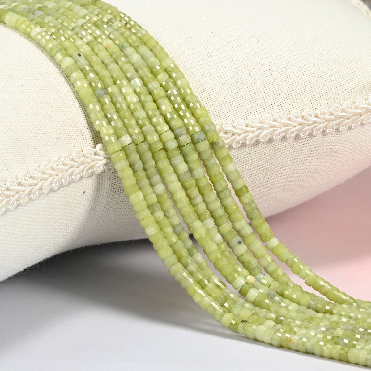 South Jade faceted heishi disc beads 2x4mm, several strands draped over a white cushion