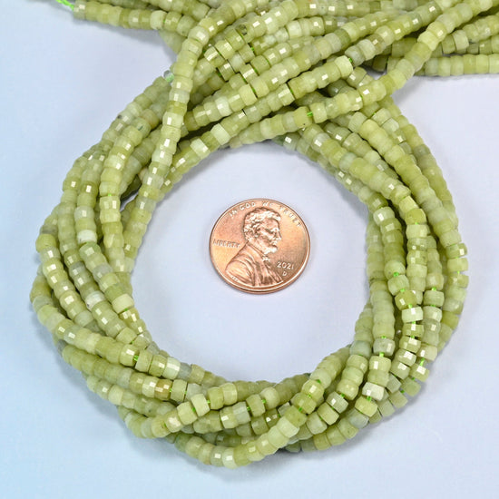 South Jade faceted heishi disc beads 2x4mm coiled in a loop around a US penny for scale, close-up of the faceted disc shape