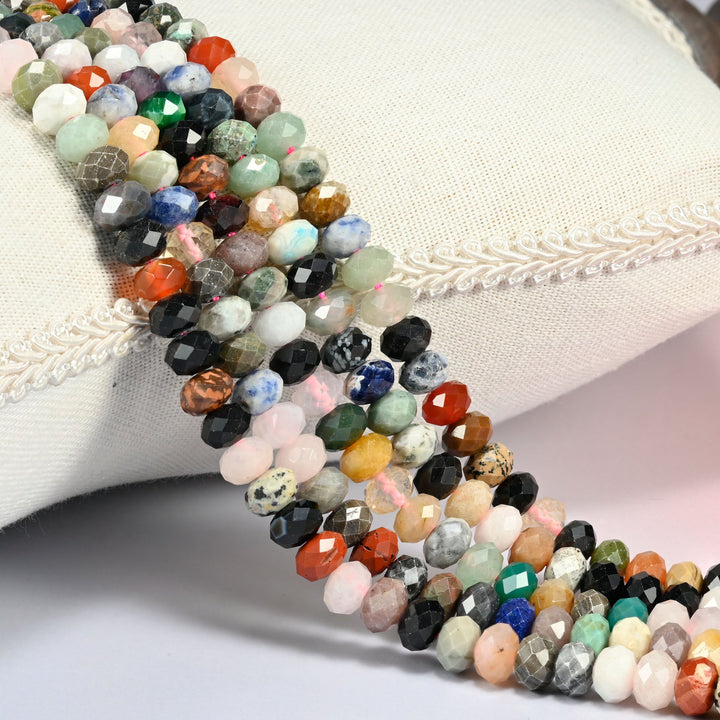 Colorful assorted gemstone faceted rondelle beads over a white cushion, many stone colors on one strand.