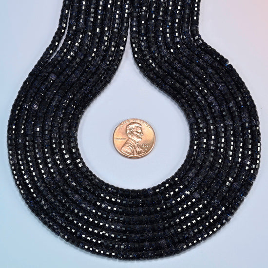 Blue sandstone faceted heishi disc strands formed into a teardrop loop around a US penny for scale