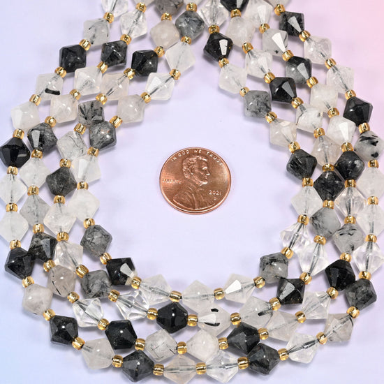 Black rutilated quartz bicone beads coiled into a ring, seen from above, facets catching the light across the coil.