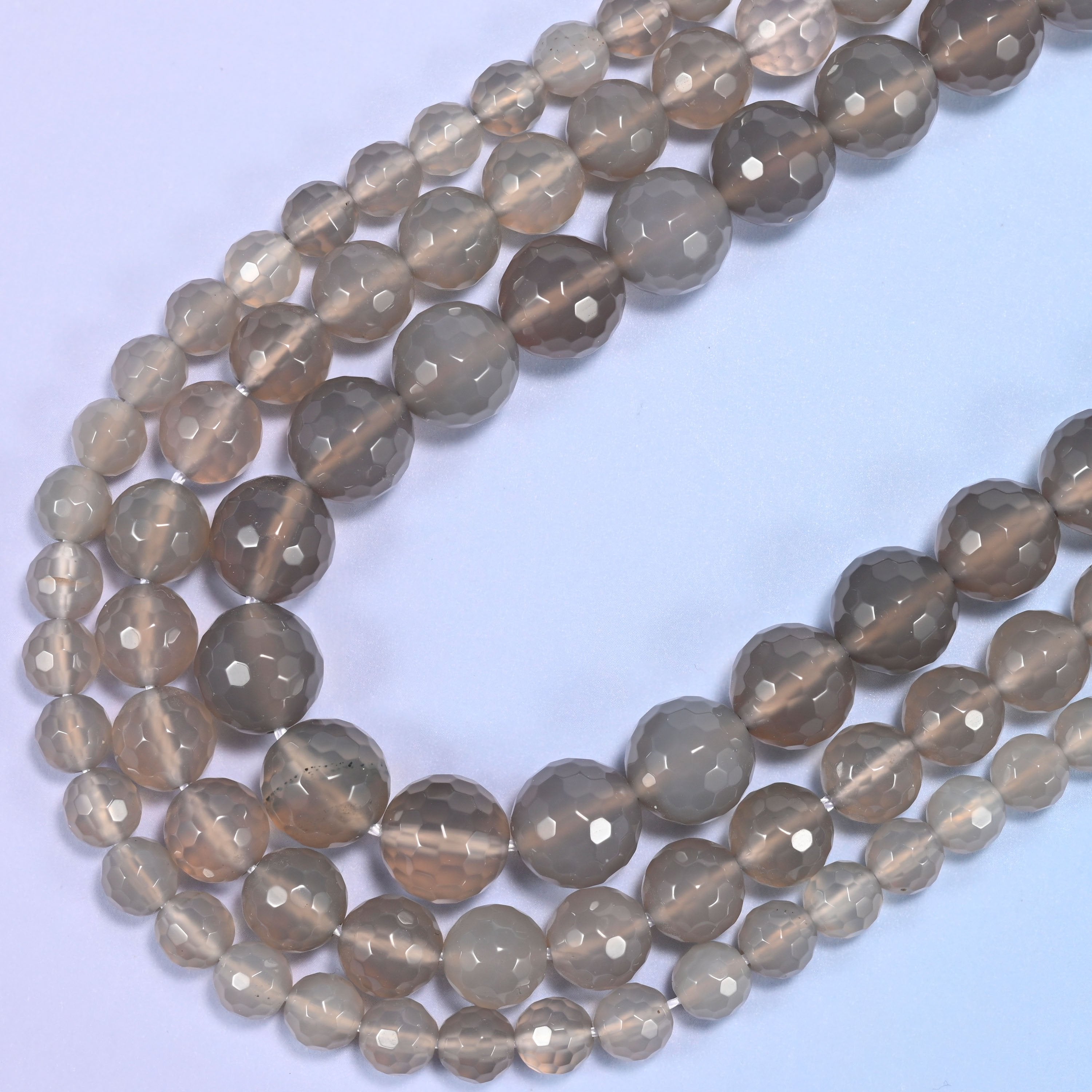 Macro detail of gray agate bead surface, highlighting the faceted texture and shine.
