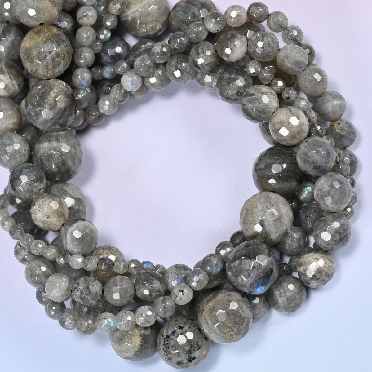 Gray Labradorite faceted round beads coiled tight, light silver beads sitting beside near-black ones on the same strand