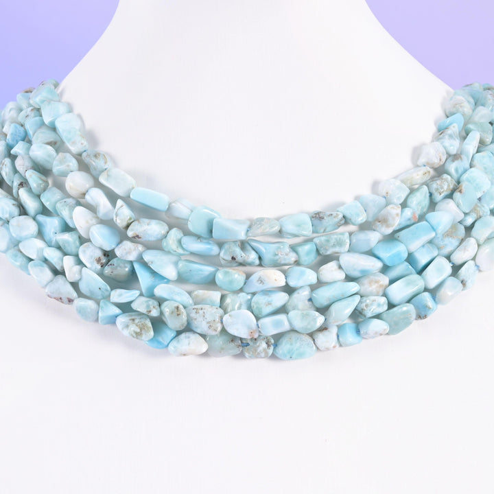 Blue Larimar irregular pebble nugget beads laid across a white necklace display, 6-8mm nuggets on a 15.5 inch strand