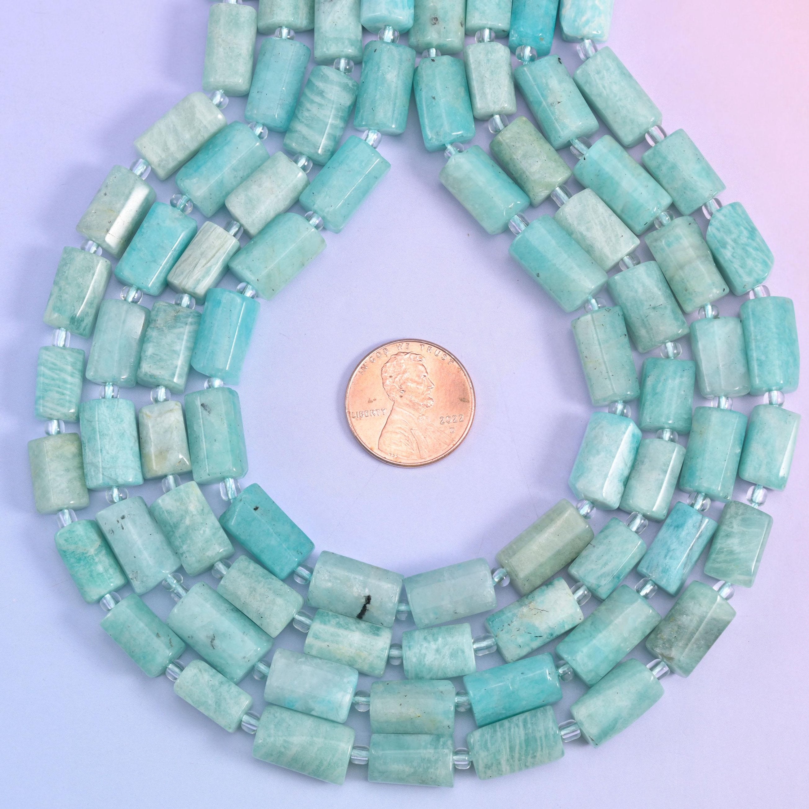 Coiled amazonite tube bead strands with a penny set at the centre for size comparison