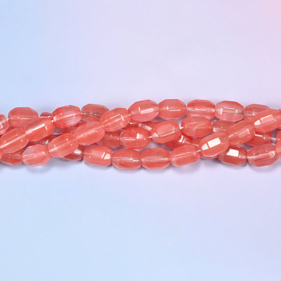 Close-up horizontal row of coral pink faceted glass barrel beads laid straight, showing the polished facet detail and translucency.