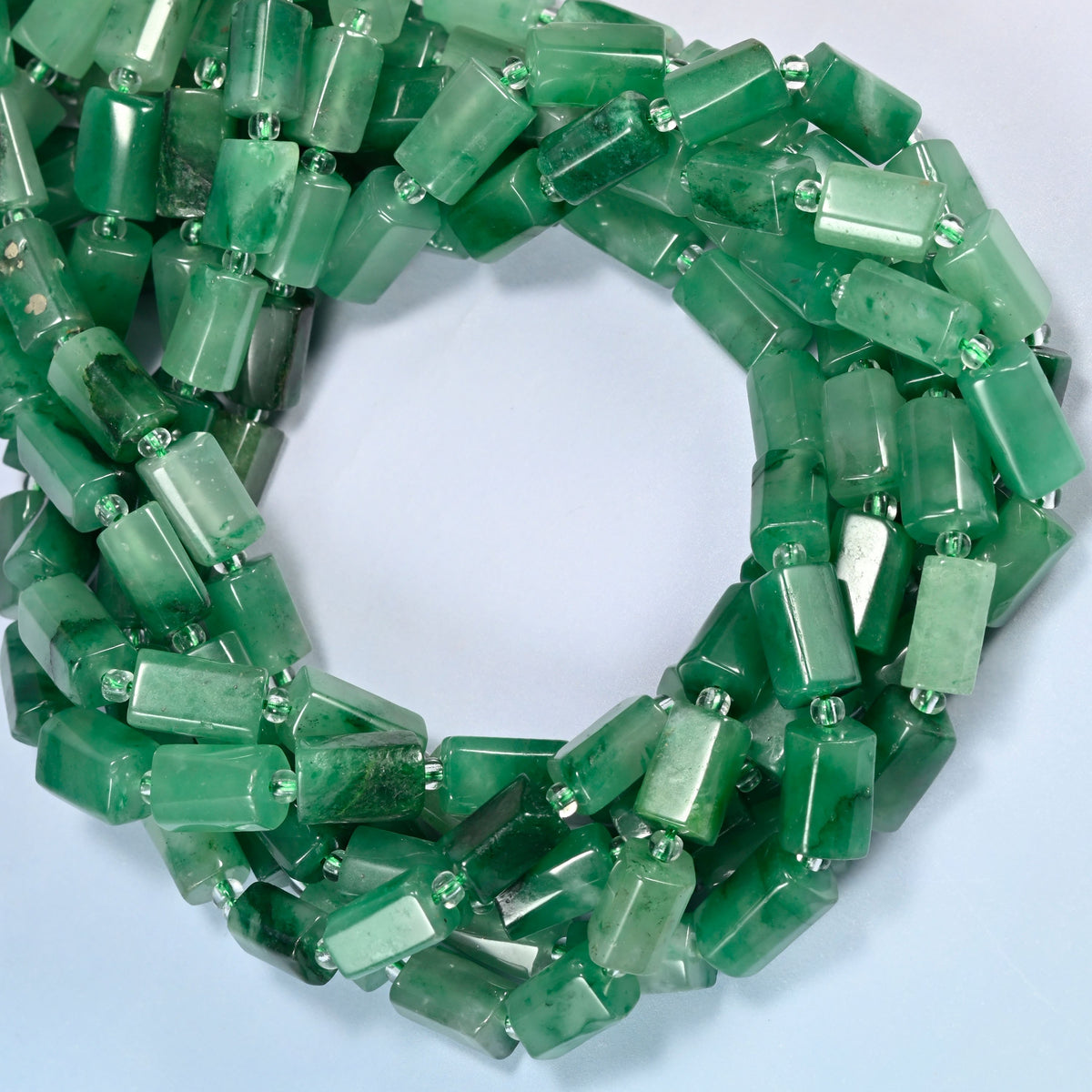 African jade faceted tube beads coiled into overlapping loops, whole strands of emerald and forest green stone