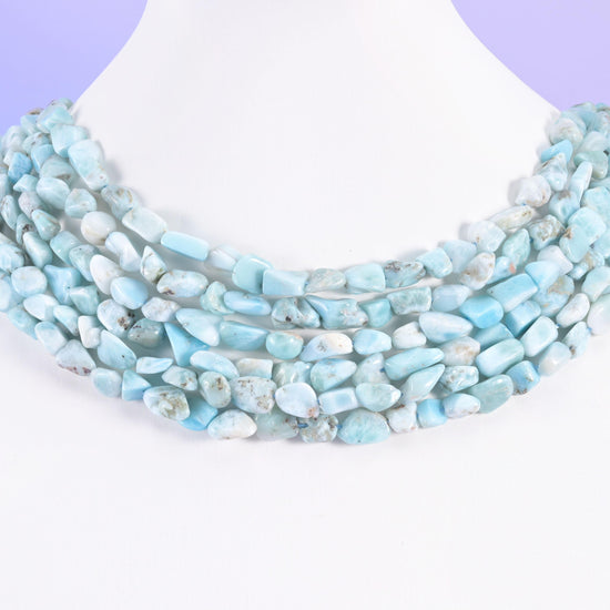 Larimar nuggets on a display bust, four rows sitting close together as a pale blue collar