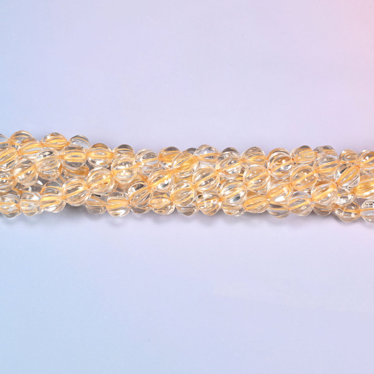 Clear gold pumpkin glass beads coiled into a ring, shown with a US penny in the open center for scale.