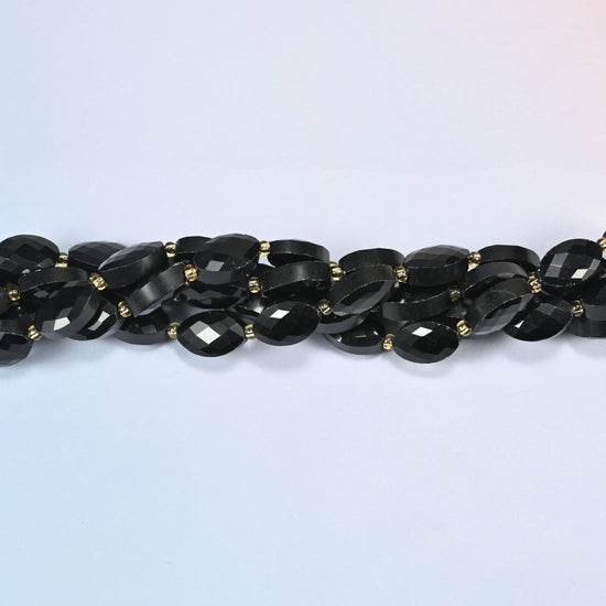 Strands of black onyx faceted flat oval beads twisted together in a horizontal row