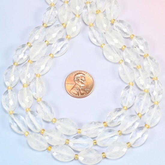 Clear quartz faceted flat oval strands formed into a teardrop loop around a US penny for scale