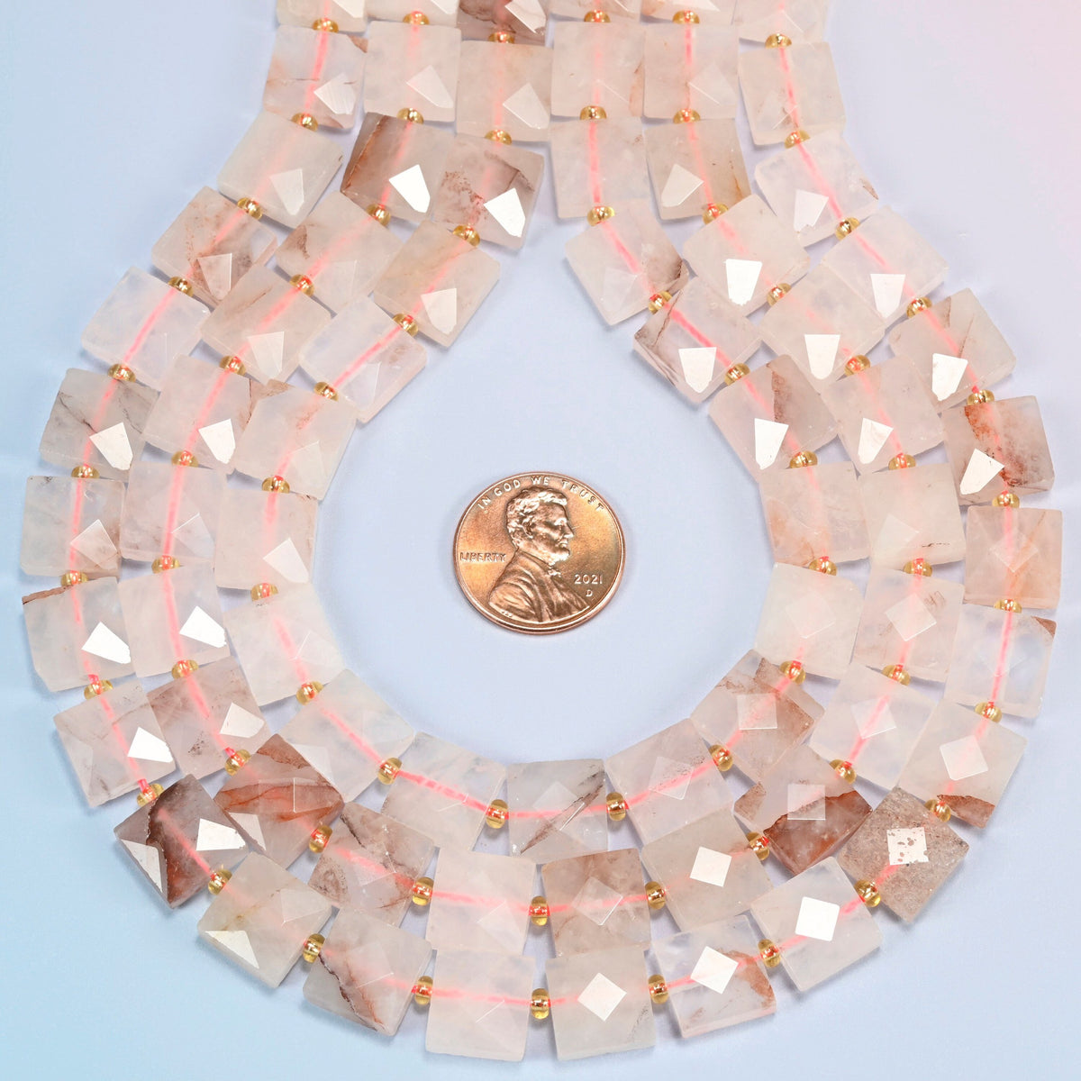 Natural red hematoid quartz faceted flat square strands formed into a teardrop loop around a US penny for scale