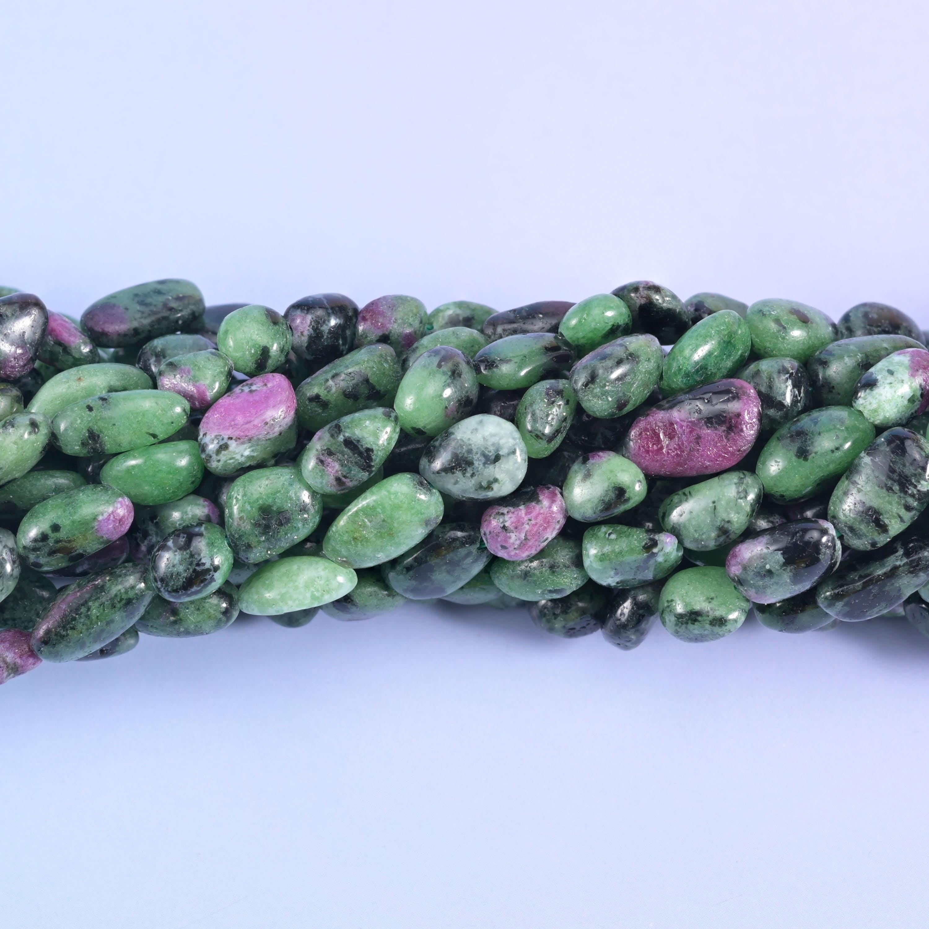 Smooth tumbled nuggets in bright apple green, streaked with charcoal-black hornblende and flecked with raspberry-pink ruby