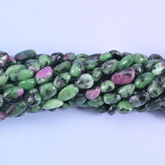 Smooth tumbled nuggets in bright apple green, streaked with charcoal-black hornblende and flecked with raspberry-pink ruby