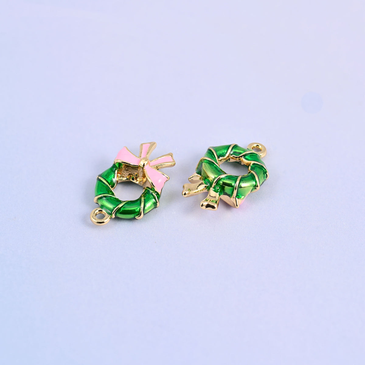 Two wreath charms lying front and back, glossy green enamel on 18K gold plated brass.