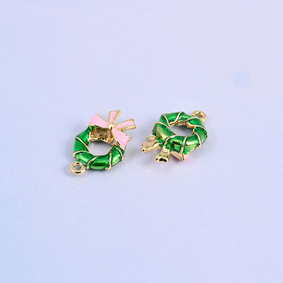Two wreath charms lying front and back, glossy green enamel on 18K gold plated brass.