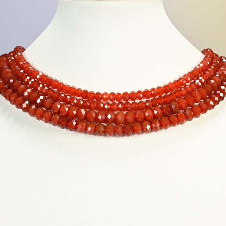 Red agate beads shown on a white neck display, the faceted rondelle strands sitting close to the neckline