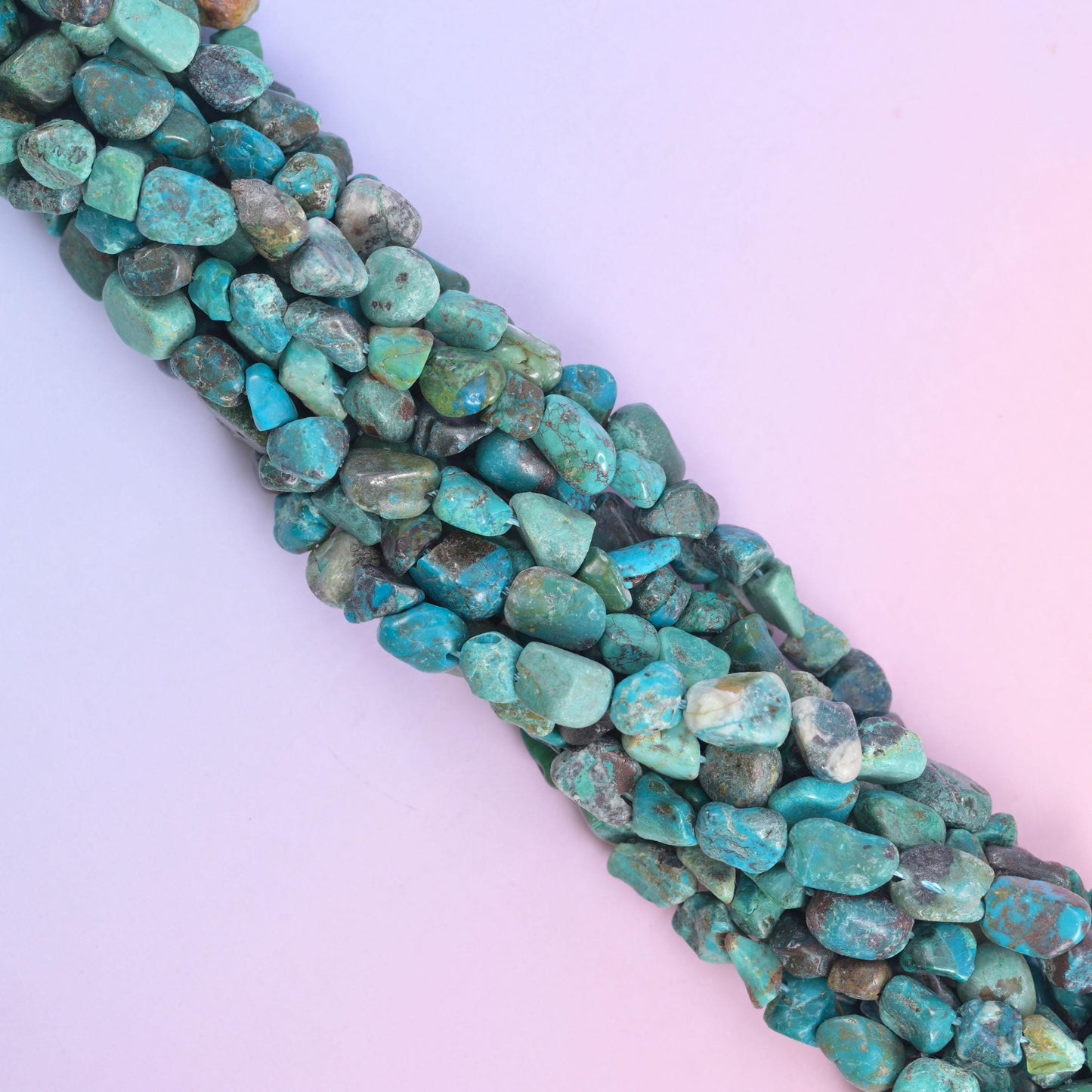 Strands running diagonally across pale lilac, deeper teal beads mixed with paler green ones
