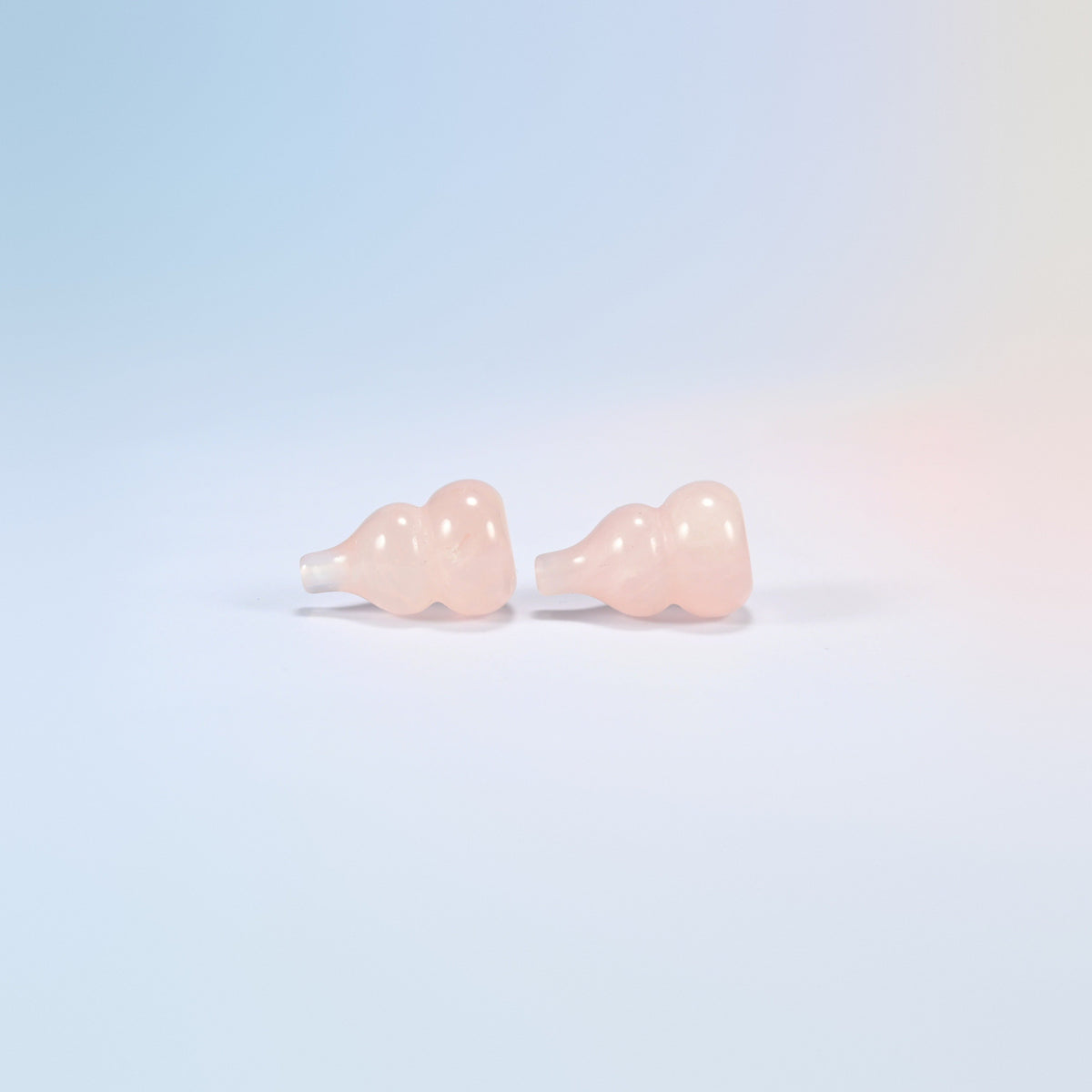Two natural rose quartz wu lou gourds lying down showing the double bulb shape