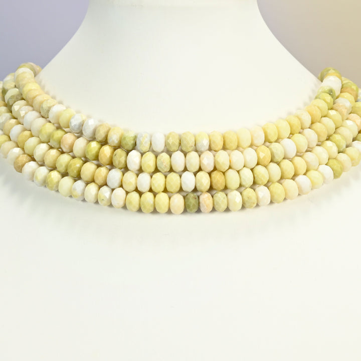 Butter jade faceted rondelle beads on a white neck display, five strands around the base of the bust.