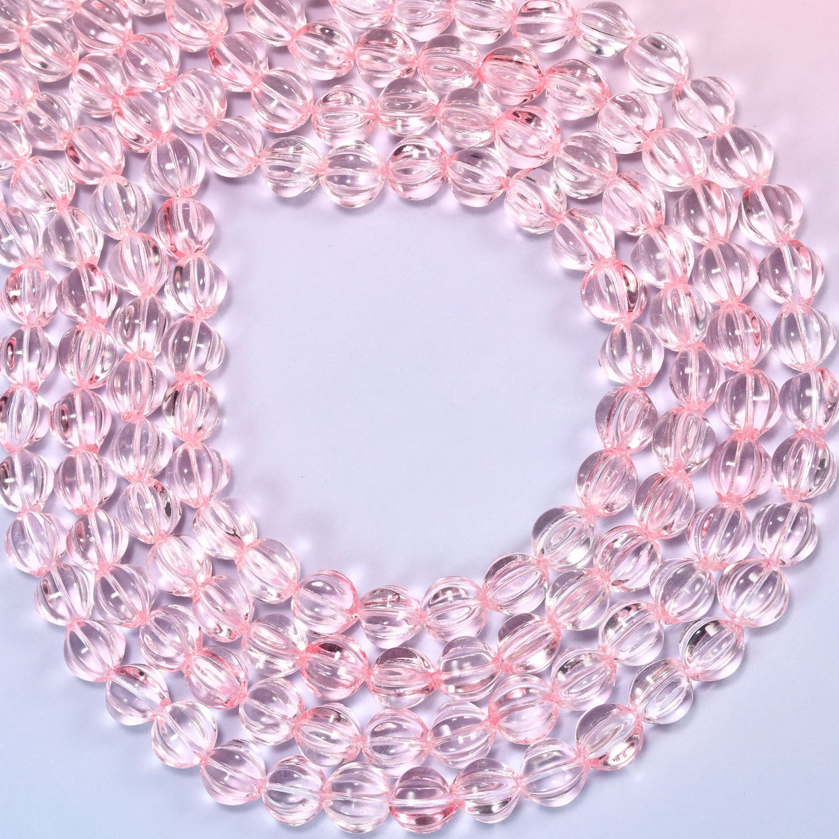 Clear pink pumpkin glass beads coiled into a ring, shown with a US penny in the open center for scale.