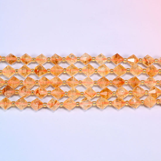Citrine bicone beads in straight rows, seen close up, each bead cut to two points meeting at a wide center.
