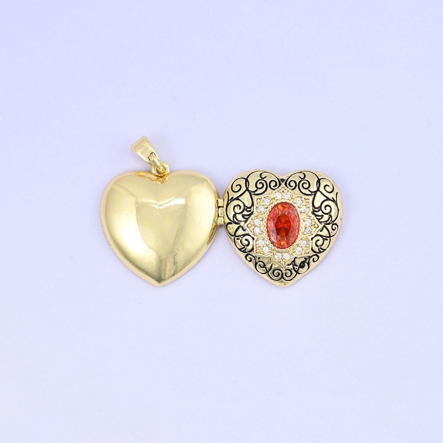 Heart locket pendant with black filigree scrollwork and red zircon centerpiece