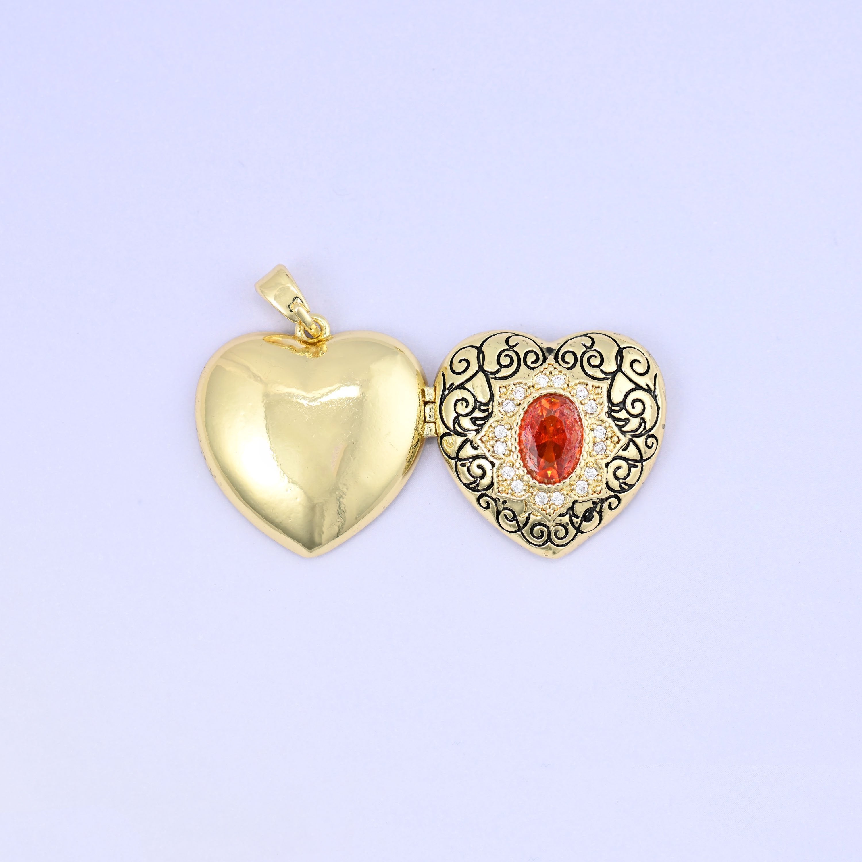 Heart locket pendant with black filigree scrollwork and red zircon centerpiece