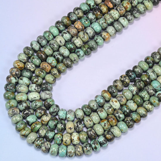 Close-up of African Howlite rondelle beads coiled in a circular arrangement on a lavender background.