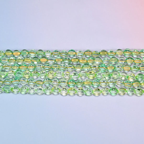 Close-up of 8mm green gold pumpkin glass beads in four horizontal rows, showing the carved melon ribs.
