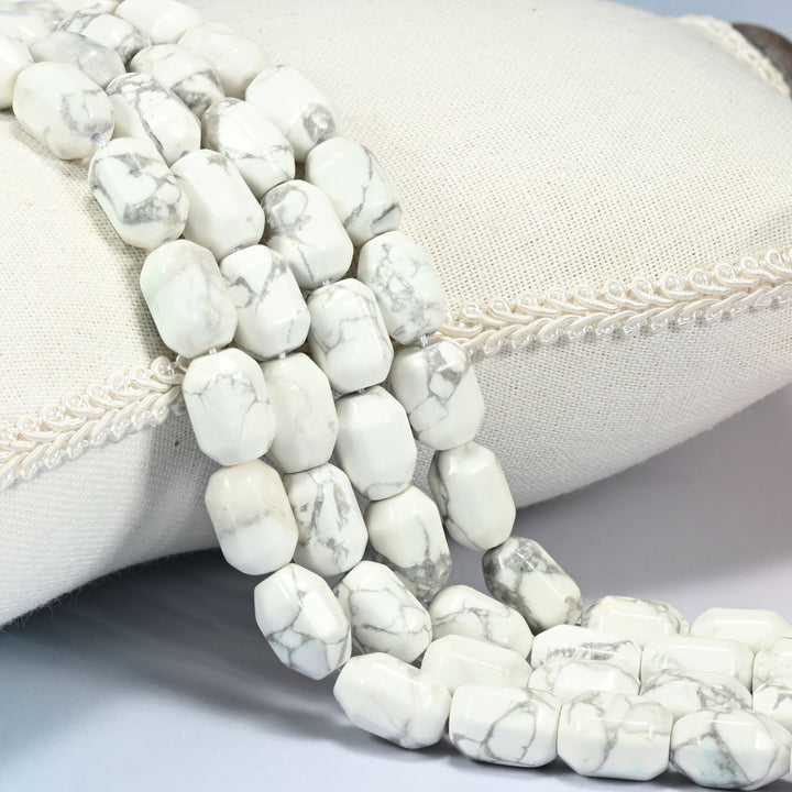 White Howlite faceted barrel drum beads draped in a soft curve, soft gray veining webbing across the white faces