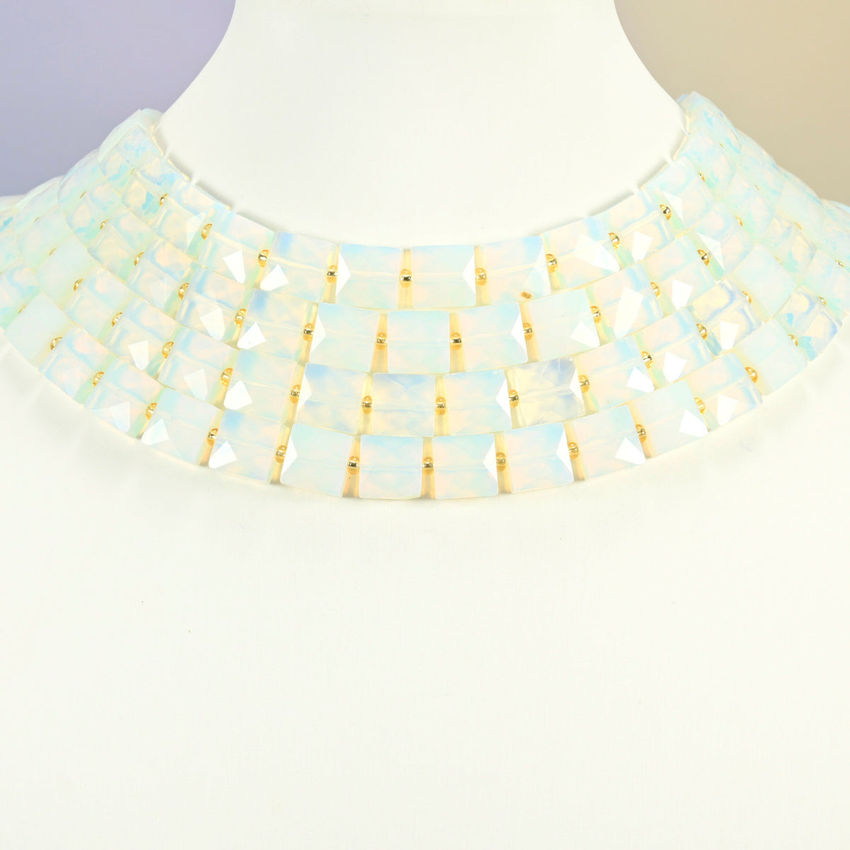 Opalite faceted flat square strands arranged as a layered collar on a white display bust, milky white beads across the neck