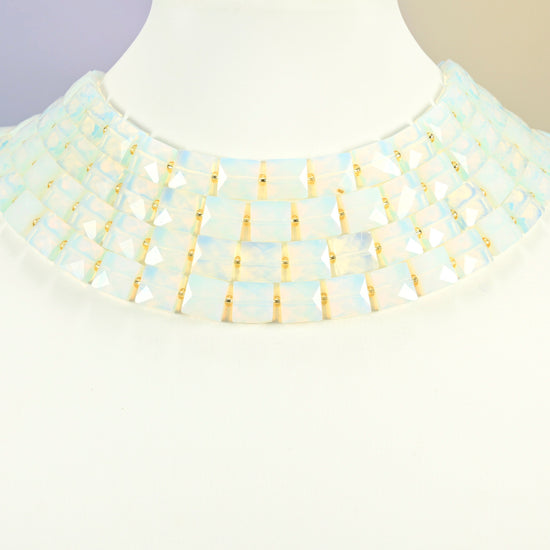 Opalite faceted flat square strands arranged as a layered collar on a white display bust, milky white beads across the neck