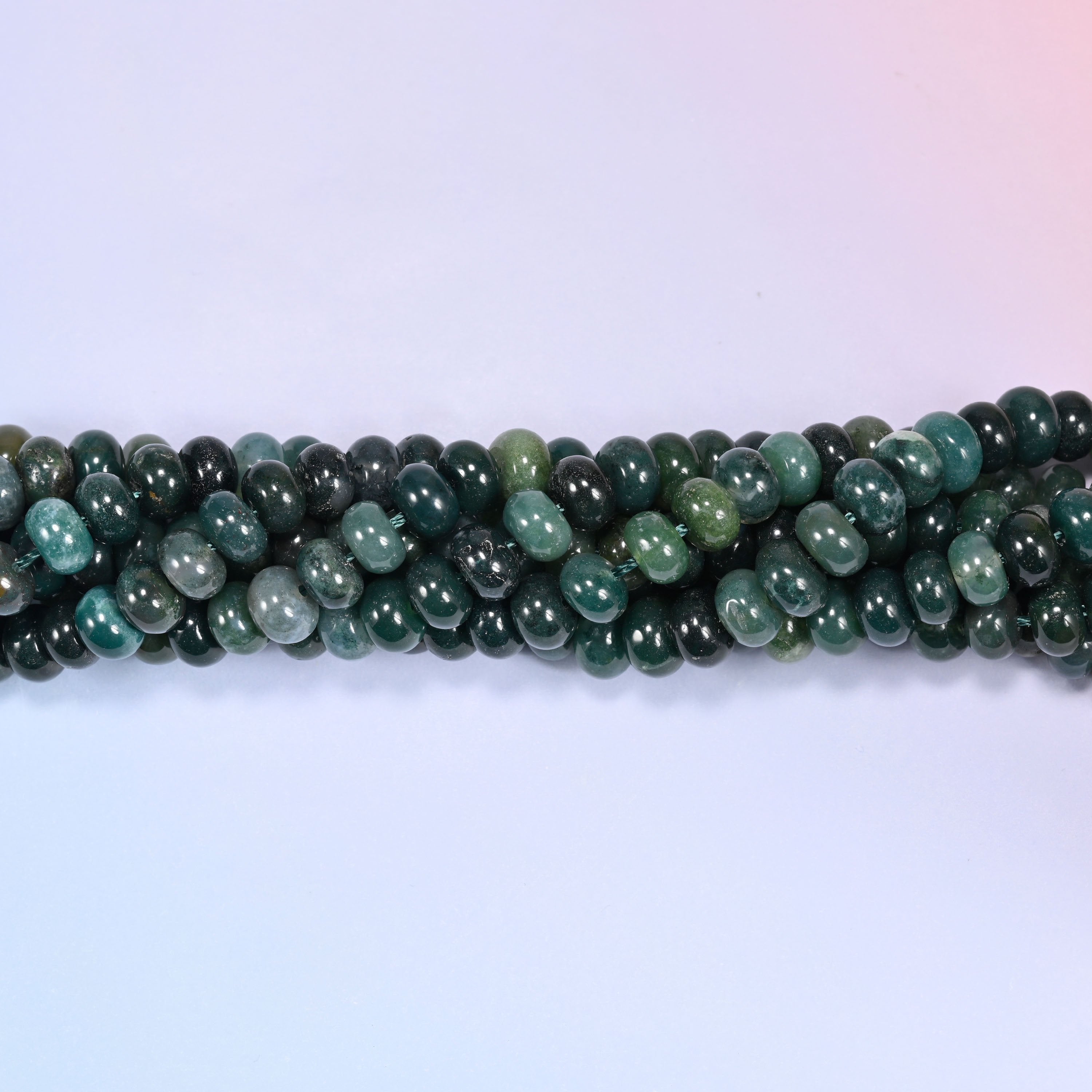 Close-up of coiled Moss Agate beads showing the natural moss-like texture.
