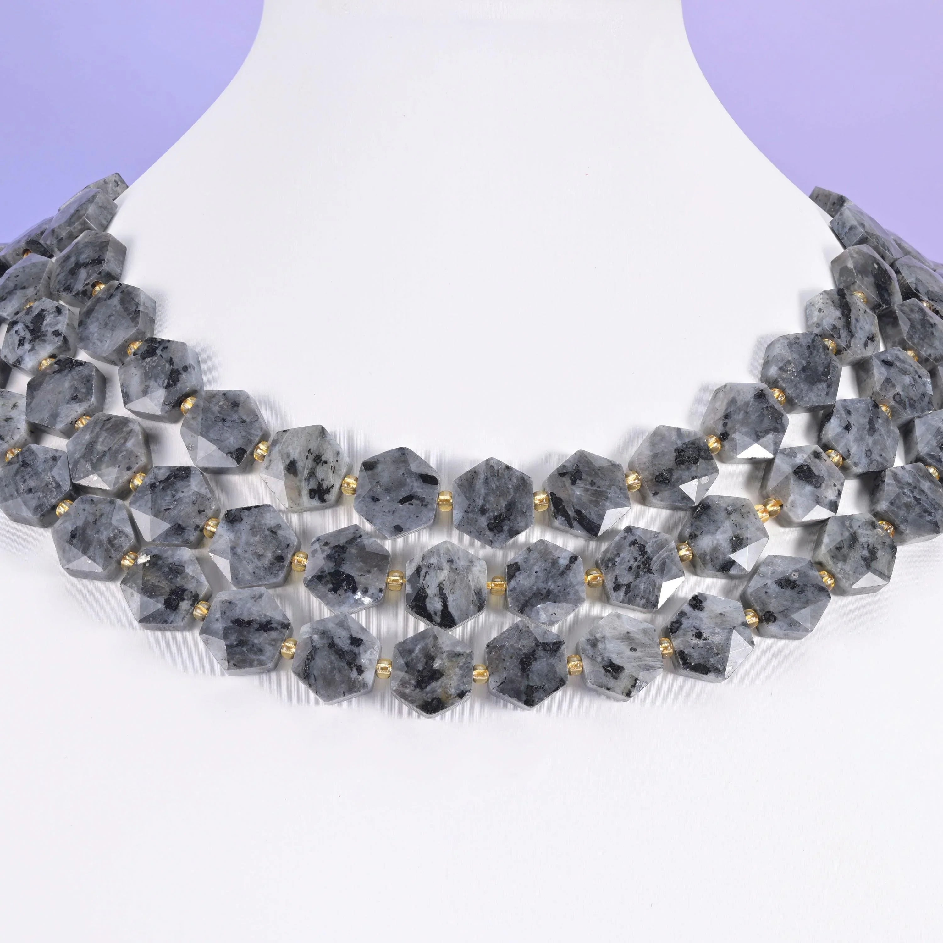 Grey Black Labradorite hexagon beads arranged across a white neck display form