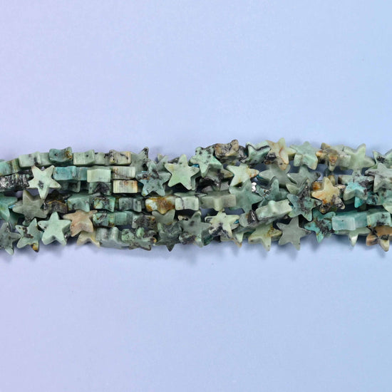 Small five-pointed stars in soft sage and celadon green, veined with dark green-black matrix and the odd warm tan fleck, polished flat on both faces.