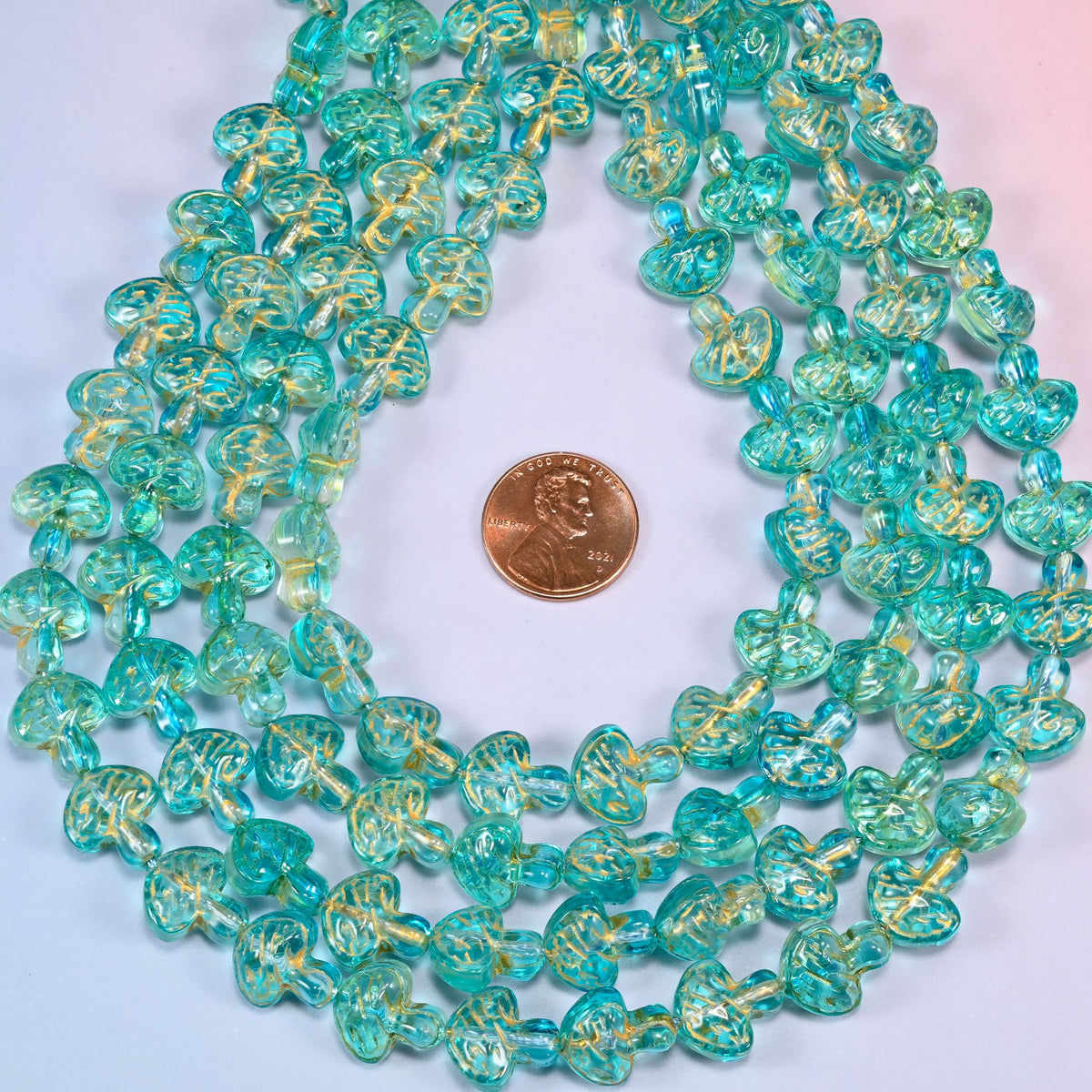 Aqua gold flat mushroom glass beads coiled flat into several concentric rings around an open center.