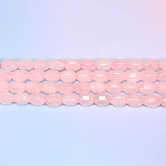 Close-up rows of Rose Quartz faceted barrel beads laid diagonally, showing the soft blush pink tone and facet cuts.
