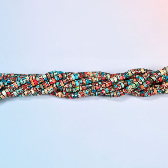 Strands of dyed red blue sea sediment jasper heishi disc beads 2x4mm twisted together in a horizontal row